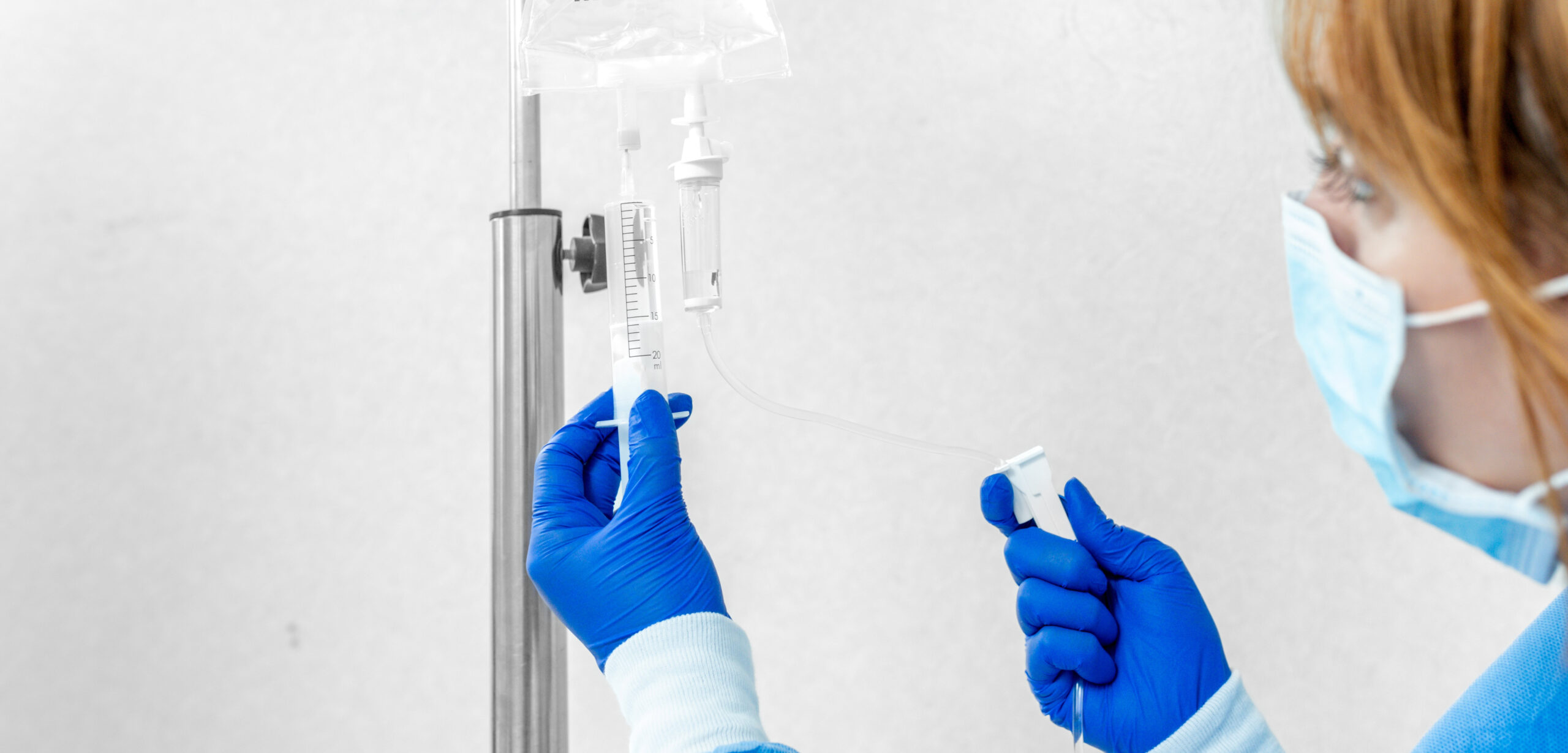 An IV Infusion nurse with sterile gloves prepping an IV bag