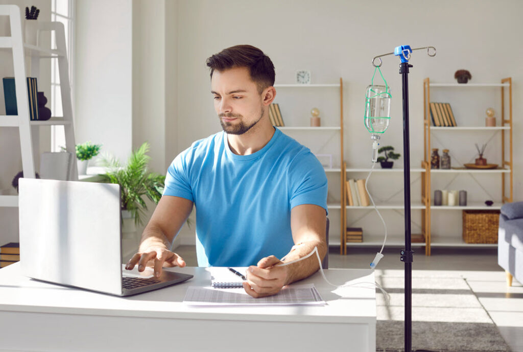 A young man in his home office receiving a mobile IV therapy vitamin drip.