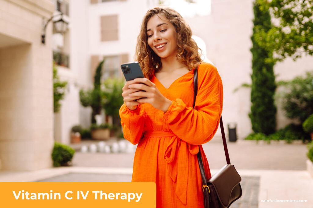 A woman in a bright orange dress smiling outdoors, representing energy, radiance, and wellness after Vitamin C IV Therapy from California Infusion Centers
